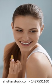 Vitamin. Smiling Woman With Omega 3 Pill, Fish Oil Capsule In Hand. Closeup Portrait Of Beautiful Girl Taking Vitamin D, E Supplement. Diet Nutrition Concept