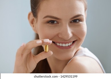 Vitamin. Smiling Woman With Omega 3 Pill, Fish Oil Capsule In Hand. Closeup Portrait Of Beautiful Girl Taking Vitamin D, E Supplement. Diet Nutrition Concept