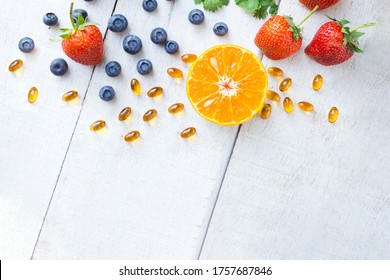 Vitamin-Ergänzung mit gesunden Früchten Heidelbeere, Erdbeere und Orange auf weißem Holzhintergrund.Draufsicht.