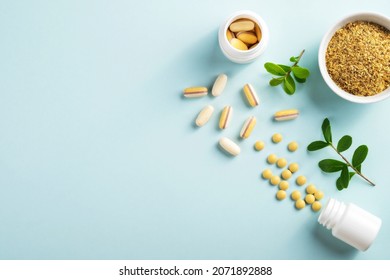 Vitamins and herbal supplements in jars with a green plant on a blue background.Biologically active additives. Dietary supplements. - Shutterstock ID 2071892888