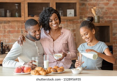 Vitamins And Minerals. Beautiful Black Family Having Breakfast Together, Girl Pouring Milk, Copy Space