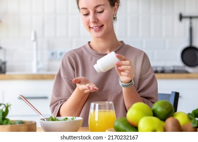 Vitamins, Nutritional Supplements, Healthy Lifestyle Concept. Young Woman Eating Breakfast And Taking Vitamin Sitting At Home In The Kitchen, Smiling Friendly