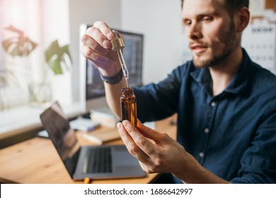 Vitamins and supplements. Hand holding pipette of Hemp oil. Close up man uses CBD oil. Medical cannabis. Healthy lifestyle