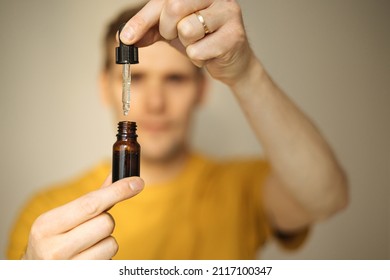 Vitamins And Supplements. Hand Holding Pipette Of Hemp Oil. Close Up Man Uses CBD Oil. Medical Cannabis. Healthy Lifestyle And Daily Dose Of Tincture