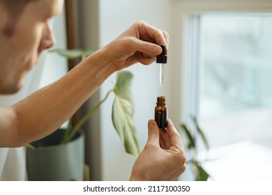 Vitamins And Supplements. Hand Holding Pipette Of Hemp Oil. Close Up Man Uses CBD Oil. Medical Cannabis. Healthy Lifestyle And Daily Dose Of Tincture