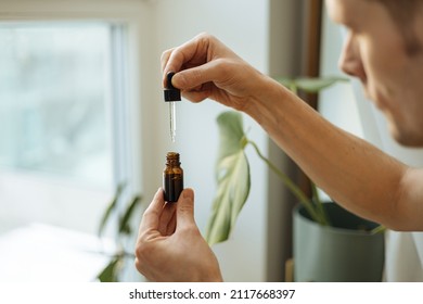 Vitamins and supplements. Hand holding pipette of Hemp oil. Close up man uses CBD oil. Medical cannabis. Healthy lifestyle and daily dose of tincture
