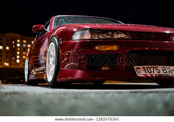 Vitebsk / Belarus - August 30, 2018: Photo of a\
Nissan 200sx s14. Red  tuning, glossy stanced drift car at gas\
station at night. Japan tuned Nissan silvia S14 zenki with sr20det\
engine. Sport wheels.