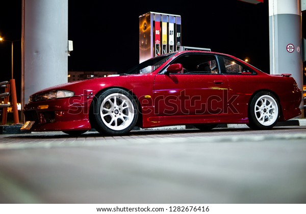 Vitebsk / Belarus - August 30, 2018: Photo of a
Nissan 200sx s14. Red  tuning, glossy stanced drift car at gas
station at night. Japan tuned Nissan silvia S14 zenki with sr20det
engine. Sport wheels.