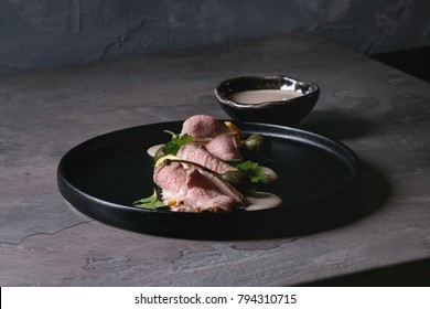 Vitello Tonnato Italian Dish. Thin Sliced Veal With Tuna Sauce, Capers And Coriander Served On Black Plate Over Dark Texture Background. Top View, Space