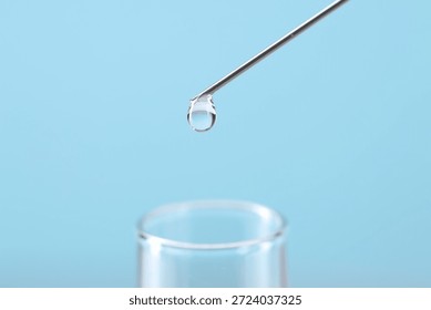 In vitro fertilization. Needle with liquid sample and test tube on light blue background, closeup