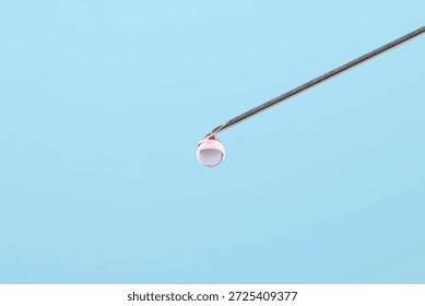 In vitro fertilization. Needle with liquid sample on light blue background, closeup. Space for text