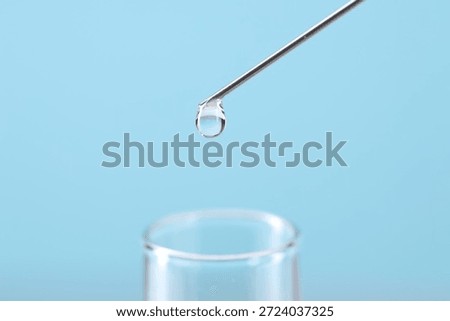 In vitro fertilization. Needle with liquid sample and test tube on light blue background, closeup