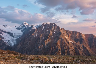 Vivid alpine landscape with high snow mountains and large glacier in sunrise colors. Colorful mountain scenery with sunlit golden rocks and mountains at sunrise. Early morning at very high altitude. - Shutterstock ID 2121539264