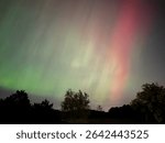 Vivid bands of green, red, and yellow aurora light up the night sky above Madison, Wisconsin, creating a rare and colorful celestial show across the Midwestern horizon.