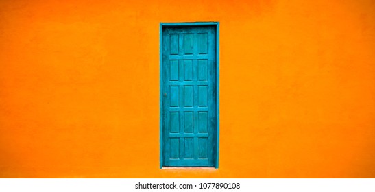 Vivid bright orange wall house facade with blue green closed door in the centre of large empty orange wide wall texture background space in panorama banner format. - Powered by Shutterstock