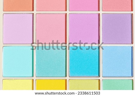 Vivid colored eye shadow makeup palette, pink, violet, blue, yellow colors. Woman cosmetic and beauty product, glitter eye shadow, aesthetic texture background, tender pastel color photo, top view