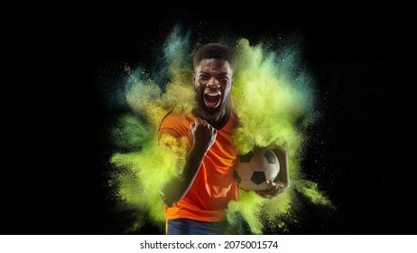 Vivid emotions of winner. Collage with young sportsman, soccer football player in explosion of colored neon powder isolated on dark background. Concept of energy, power, motion. Copyspace for ad