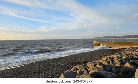 Vivid hues paint the sky as the sun dips below the horizon, casting a warm glow over the tranquil rocky beach. Sunrise brings a burst of colour, igniting the sky with hues of orange, pink, and gold.  - Powered by Shutterstock