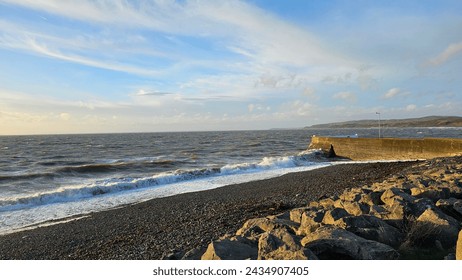 Vivid hues paint the sky as the sun dips below the horizon, casting a warm glow over the tranquil rocky beach. Sunrise brings a burst of colour, igniting the sky with hues of orange, pink, and gold.  - Powered by Shutterstock