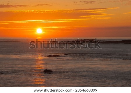 Vivid orange and red summer sunset over the island of Burhou just off Alderney in the UK Channel Islands