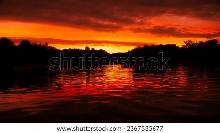 A vivid orange sunset over Deep Creek Lake in Maryland, with silhouetted mountains in the background