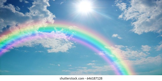 Vivid Rainbow Sky Website Banner  -  Wide blue sky with pretty clouds, a bright sun shining center top and a large rainbow arcing from left to right with copy space