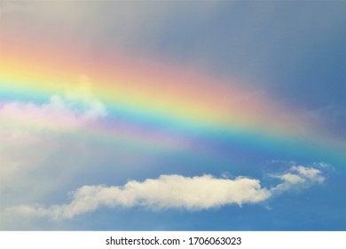 A Vivid Rainbow Streaking Across Blue, Cloudy Skies. 