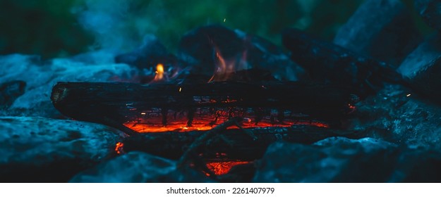 Vivid smoldered firewoods burned in fire close-up. Atmospheric warm background with orange flame of campfire and blue smoke. Wonderful full frame image of bonfire. Burning logs in beautiful fire. - Powered by Shutterstock