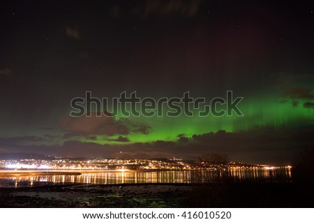 vivid strong aurora borealis over the arctic city of tromsoe in late autumn