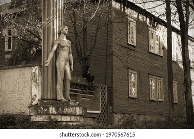 Vladikavkaz, North Ossetia, Russia - 2016 04 17: A boy and a statue of a worker woman beside the Dinamo plant entrance in Vladikavkaz city. Those women with paddles encouraged soviet people to work.