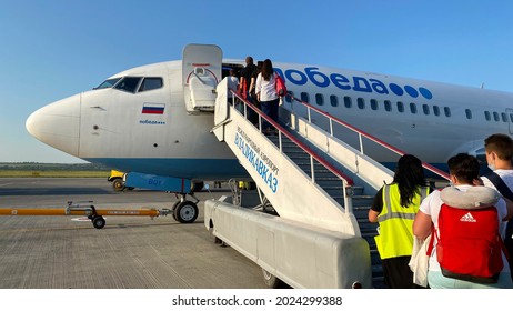 VLADIKAVKAZ, RUSSIA - JULY 20, 2021: People Walk The Ladder Aboard The Plane Of Pobeda Airlines.