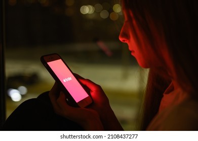 Vladimir, Russia - January 2022: Tinder dating app on a smartphone in the hands of a girl at night. Selective focus on the logo, narrow focus.