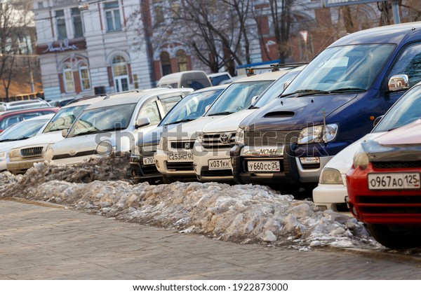 Vladivostok, Russia, 2017 -\
Cars stand in a dirty roadside. Snowdrift on the background of\
parked cars