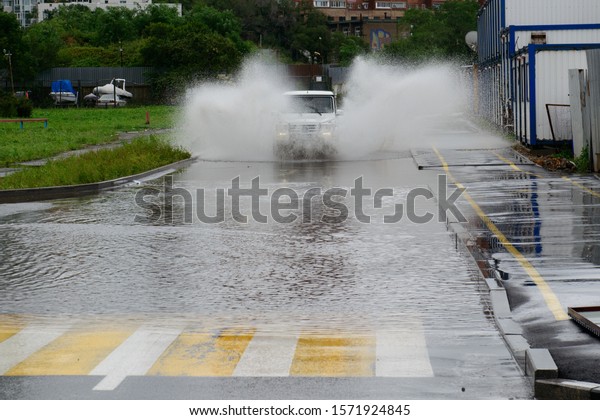 Vladivostok, Russia - August 27, 2015: The\
off-road vehicle is fast on a deep\
puddle.