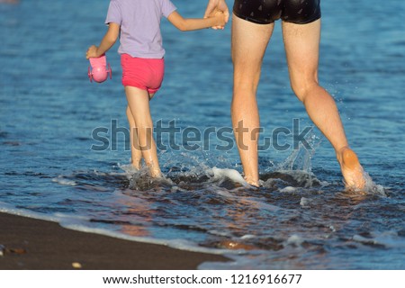 Vladivostok, Russia-September 1, 2018: A man and a girl walking along the shore in the spray of sea water