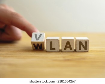 Vlan to wlan network type concept. Finger flips letter at wooden cube changing the word vlan to wlan. Message for security with logically independent network against wider connection. 