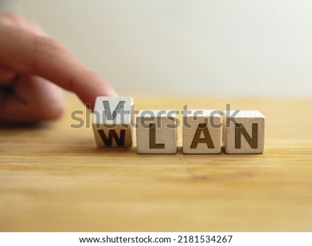 Vlan to wlan network type concept. Finger flips letter at wooden cube changing the word vlan to wlan. Message for security with logically independent network against wider connection. 