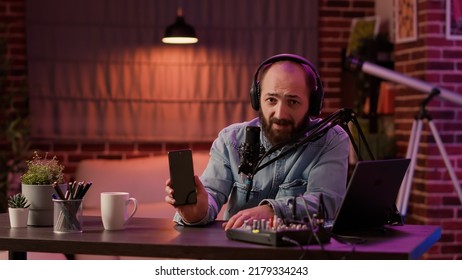 Vlogger influencer recording product review for modern smartphone with professional audio equipment in home podcast studio. Content creator brodcasting presentation for digital touchscreen device. - Shutterstock ID 2179334243