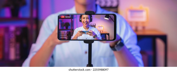 Vlogger live streaming podcast review on social media, Young Asian woman use microphones wear headphones with smartphone record video. Content creator concept. - Shutterstock ID 2255988097