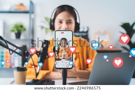 Vlogger live streaming podcast review on social media, Young Asian woman use microphones wear headphones with laptop record video. Content creator concept.