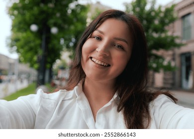 Vlogger traveler woman recording video on phone camera share via app her travel vacation in the city. Gen Z Plus size girl influencer shooting social media stories on the street. Part of a series. UGC - Powered by Shutterstock