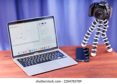 Vlogger Workplace. Laptop, Smartphone And SLR Camera On A Wooden Table. Camera On A Mini Tripod For Vlogging. Video Blogging Concept