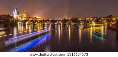 Vltava River with boat neon light lines and Charles Bridge with Old Town Bridge Tower by night, Prague, Czechia. UNESCO World Heritage Site.