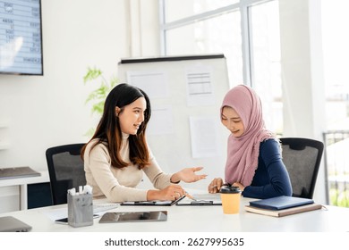 vMuslim asian businesswoman scanning contract. Business women wearing hijabs, sitting in meeting room  and reading document. Signing agreement concept.