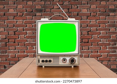 Vntage portable television with wood table, brick wall and chroma key green screen. - Shutterstock ID 2270473897