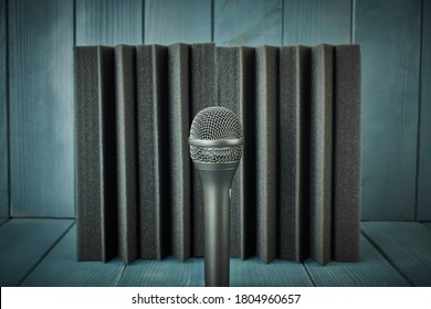 Vocal And Chorus Microphone With Grille And Capsule In The Foreground, Professional, Metallic, With Acoustic Foam And Wood Background In Gray And Blue Colors