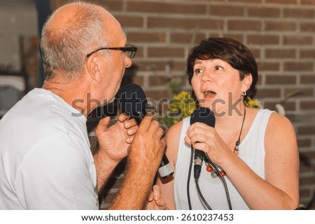 Vocal lessons. An elderly man shows a woman singing techniques with eye contact