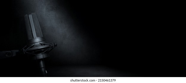 Vocal microphone on dark concrete background. Urban radio, music production or podcast banner with copy space for website header - Shutterstock ID 2150461379