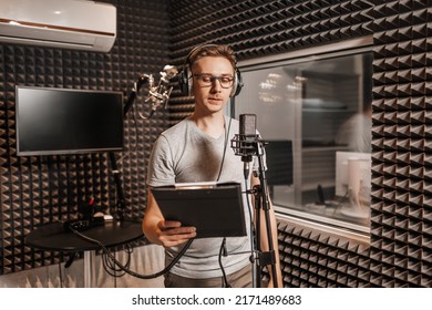 The vocalist sings in the studio in a microphone. Man in headphones writes a podcast, an audiobook. Artist, recording an album, working with the label. Announcer records a speech at a radio station - Shutterstock ID 2171489683