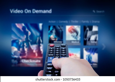 VOD service screen with remote control in hand. Video On Demand television internet stream multimedia concept